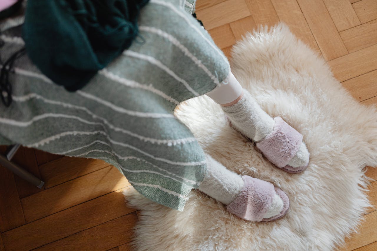 Top view of fuzzy slippers on a sheepskin rug, evoking warmth and comfort.